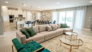 A modern living room with a beige sofa, green ottomans, and a glass coffee table.