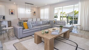 Un salon moderne avec un canapé d’angle gris, une table basse en bois et une vue sur l’extérieur.