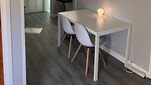 Un comedor moderno con una mesa y sillas blancas, un cuadro en la pared y una lámpara en el techo.