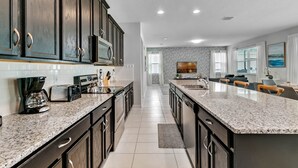 A modern kitchen with dark wood cabinets, granite countertops, and stainless steel appliances. - Last Minute Disney! Private Pool, Hot Tub, Game Room & Themed Bedrooms. Book Now! #65671 (Orlando)