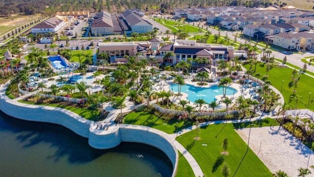 An aerial view of a residential area with a large swimming pool surrounded by houses and greenery. - Last Minute Disney! Private Pool, Hot Tub, Game Room & Themed Bedrooms. Book Now! #65671 (Orlando)