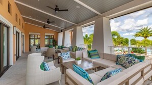 A covered outdoor seating area with sofas and chairs, a dining table, and ceiling fans. - Last Minute Disney! Private Pool, Hot Tub, Game Room & Themed Bedrooms. Book Now! #65671 (Orlando)