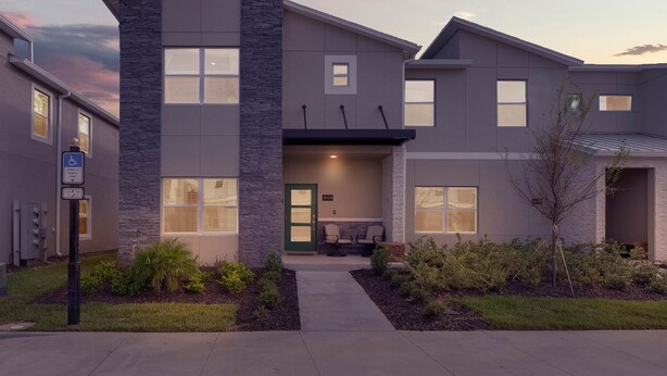 A modern building with a stone facade, multiple windows, and a well-maintained front yard. - Last Minute Disney Getaway! Private Pool & Themed Bedrooms. Book Now! #65717 (Orlando)