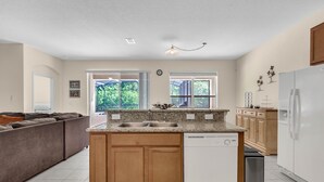 A modern kitchen with wooden cabinets, a dishwasher, and a refrigerator. - Last Minute Disney Getaway! Luxury Villa with Private Pool. Book Now! #65721 (Orlando)