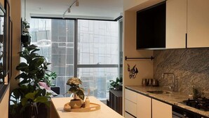 A modern kitchen with a marble island, black cabinets, and a large window.