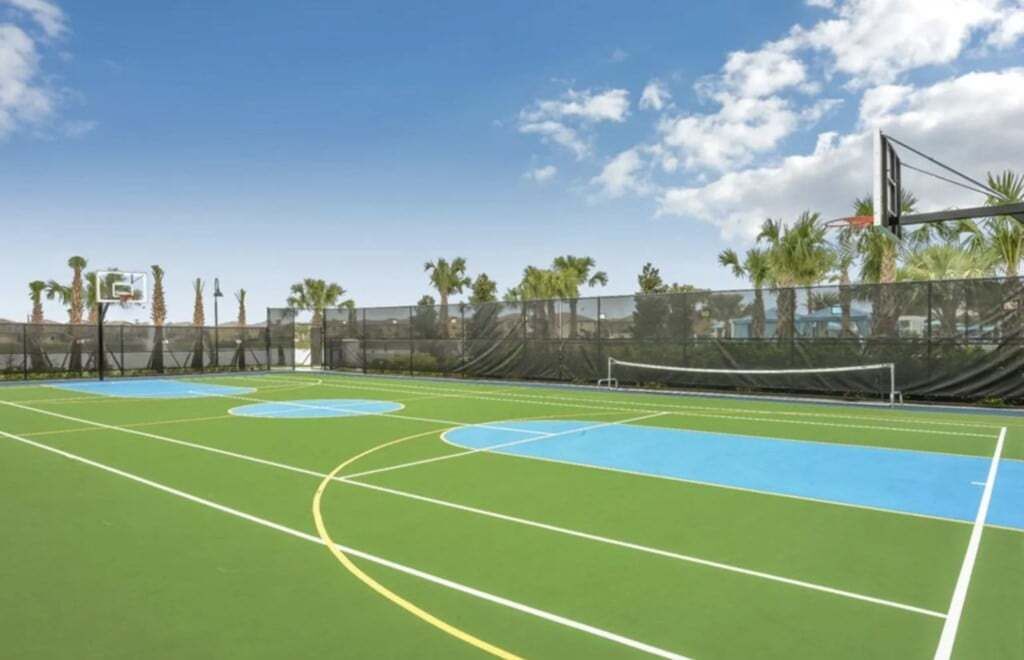 Een buitenbasketbalveld met een net, omringd door een hek en palmbomen.