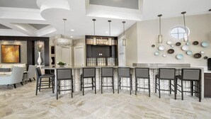 A modern kitchen with a central island, bar seating, and a dining area with a sofa and chairs. - Last Minute Disney Getaway! Private Pool, Hot Tub & Game Room. Book Now! #65771 (Orlando)