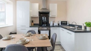 A modern kitchen with white cabinets, a central range hood, a microwave, and a sink. - 1 Bed Manchester Apartment with Parking - Sleeps 3 (Salford)