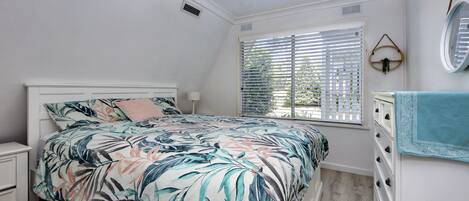 Un dormitorio con cama, cómoda, ventana con persianas y espejo en la pared.
