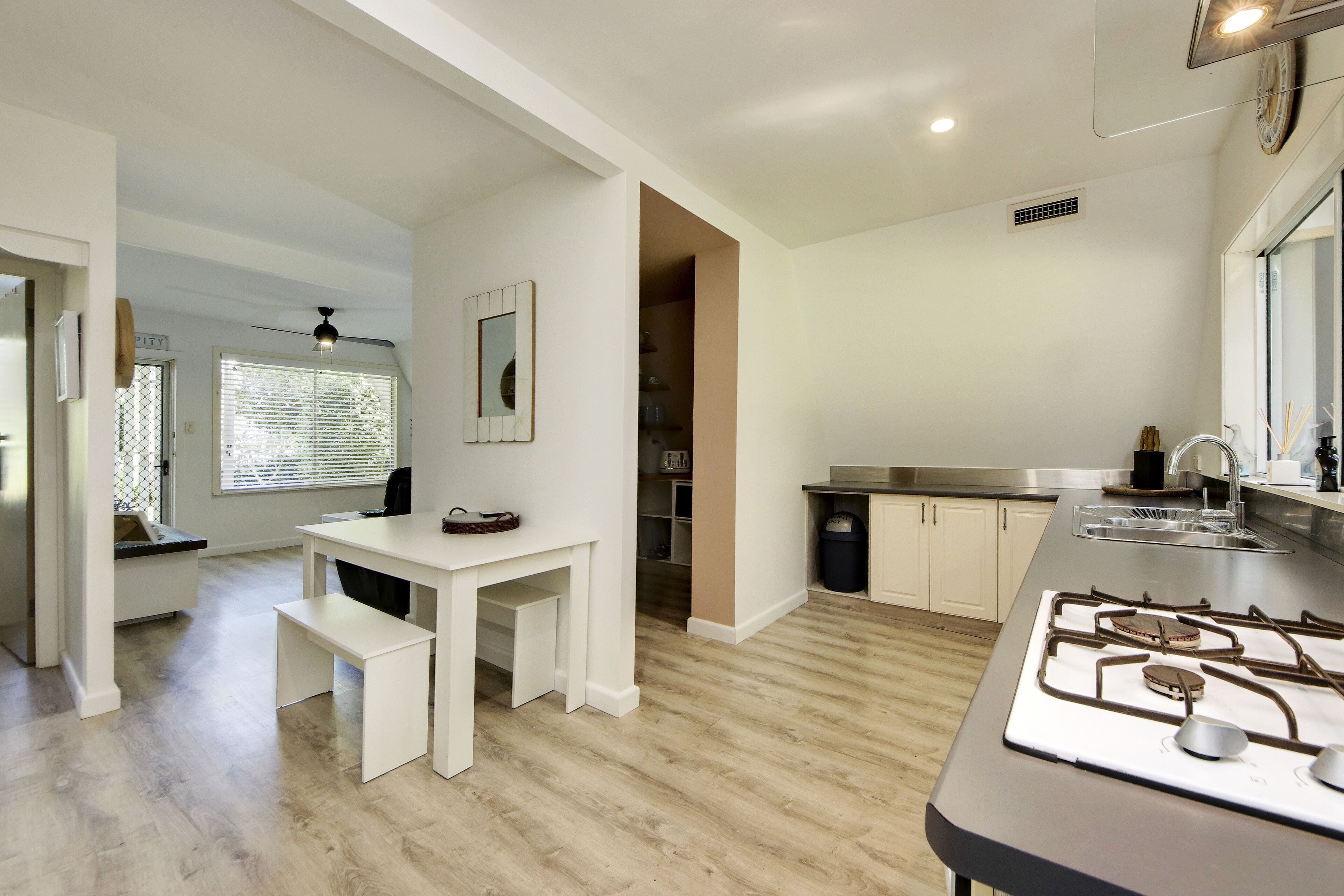 A modern kitchen with white cabinetry, a gas stove, and a dining area with a bench.
