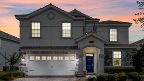 A two-story house with a garage, a blue door, and a stone facade. - Last Minute Disney! Private Pool, Hot Tub, Game Room & Themed Bedrooms. Book Now! #65909 (Orlando)