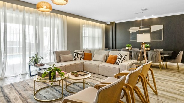 A modern living room with a sectional sofa, round coffee table, and dining area with chairs. - Last Minute Disney! Private Pool, Hot Tub, Game Room & Themed Bedrooms. Book Now! #65909 (Orlando)