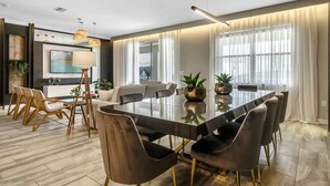 A modern dining room with a glass table, dark chairs, and a view of the outdoors through large windows. - Last Minute Disney! Private Pool, Hot Tub, Game Room & Themed Bedrooms. Book Now! #65909 (Orlando)