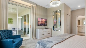 A bedroom with a large bed, a TV, a dresser, and a chair.