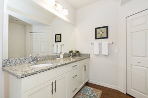 Bathroom features two sinks, a countertop, and a large mirror.