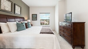 Een slaapkamer met een groot bed, een dressoir en een televisie.