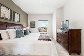 Cozy retreat with a large bed, dresser, and flat-screen TV.