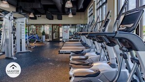 A gym with treadmills, exercise machines, and large windows. - Last Minute Disney! Private Pool, Hot Tub & Themed Bedrooms. Book Now! #66161 (Orlando)