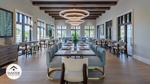 A spacious dining area with long tables and chairs, large windows, and a modern chandelier. - Last Minute Disney! Private Pool, Hot Tub & Themed Bedrooms. Book Now! #66161 (Orlando)