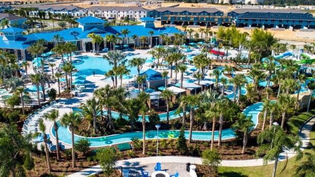 Ein Resort mit mehreren Schwimmbecken, Palmen und einem großen Gebäude mit blauem Dach.