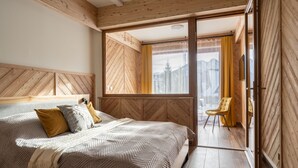 Een slaapkamer met een groot bed, een houten hoofdeinde en uitzicht op bergen door een raam.