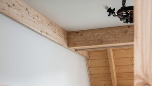 Una habitación acogedora con techo de madera, una cama con almohadas, una mesita de noche y una silla.