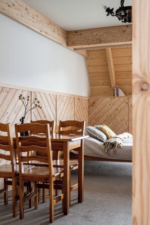 Una habitación acogedora con techo de madera, una cama con almohadas, una mesita de noche y una silla.