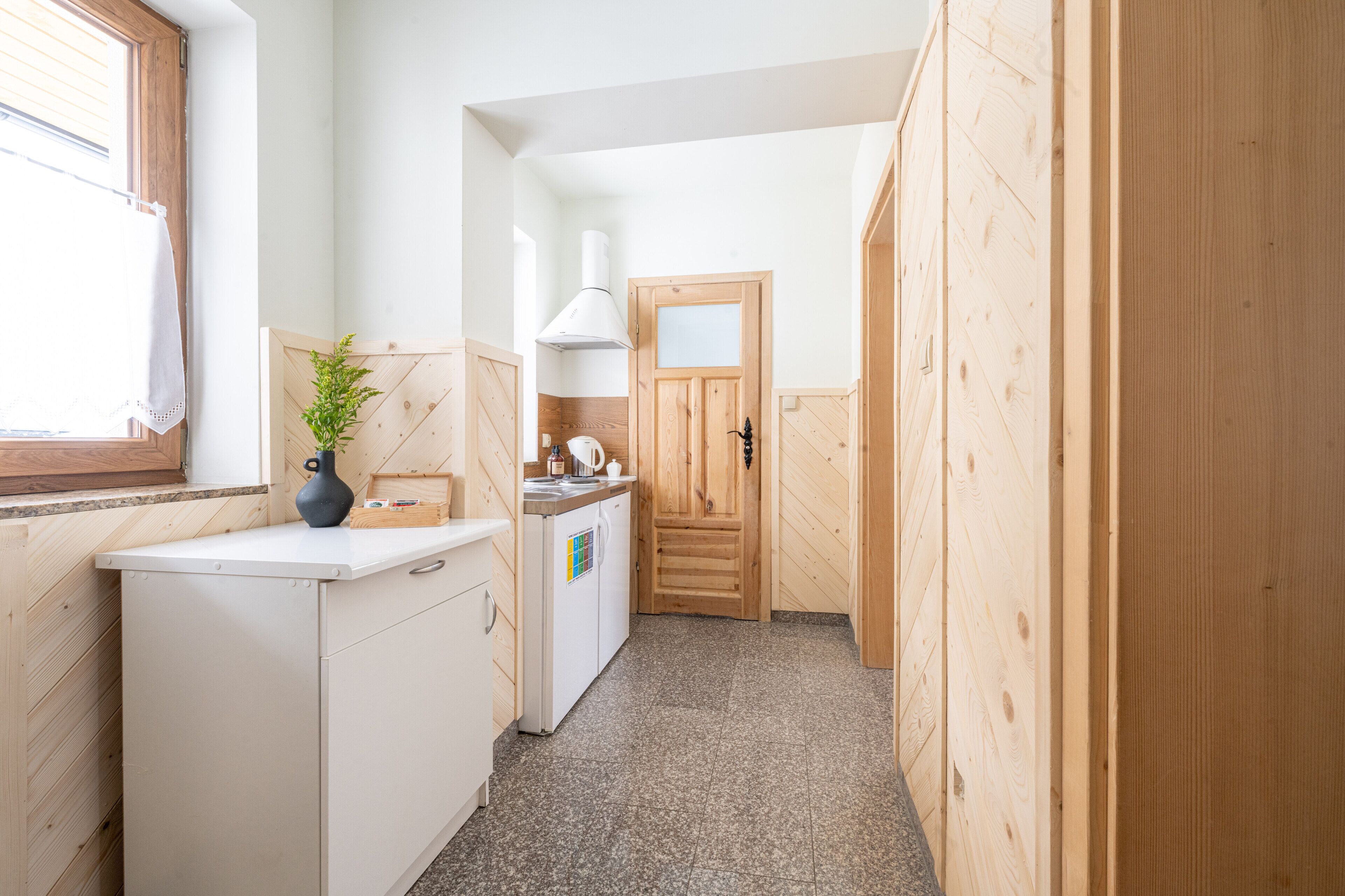 Una cocina estrecha con paredes de madera, una encimera blanca, un fregadero y una estufa.