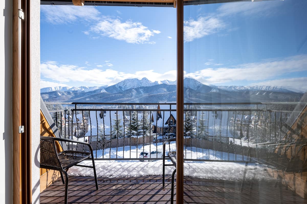 Un balcon offrant une vue sur des montagnes enneigées et une terrasse en bois.