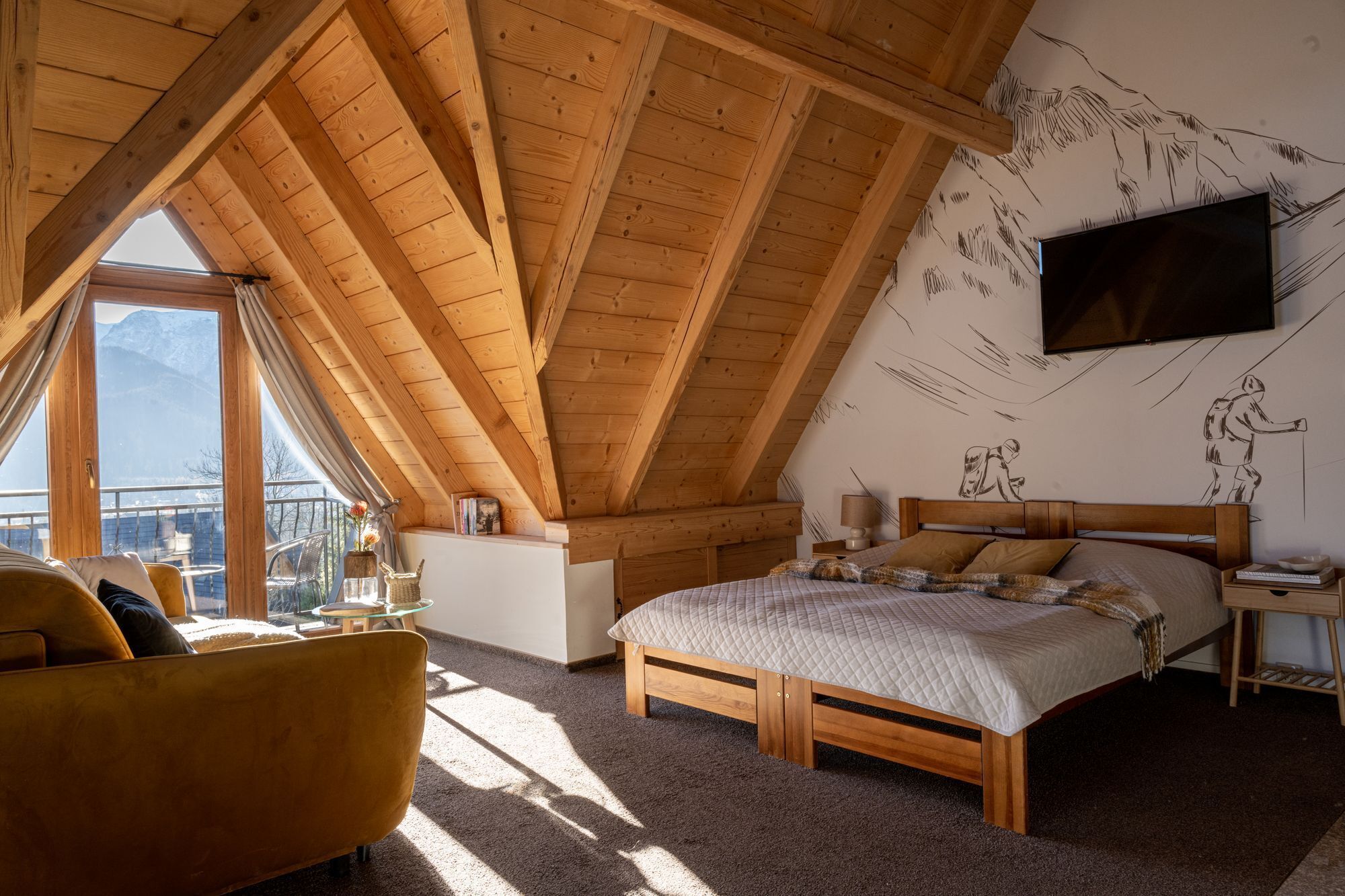 Ein Schlafzimmer mit Schrägen, einem Bett, einem Fernseher und Bergblick durch ein Fenster.