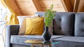 A cozy room with a gray sofa, a glass coffee table, and a plant.