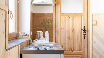 A compact kitchen with a built-in stove, sink, and a wooden backsplash.
