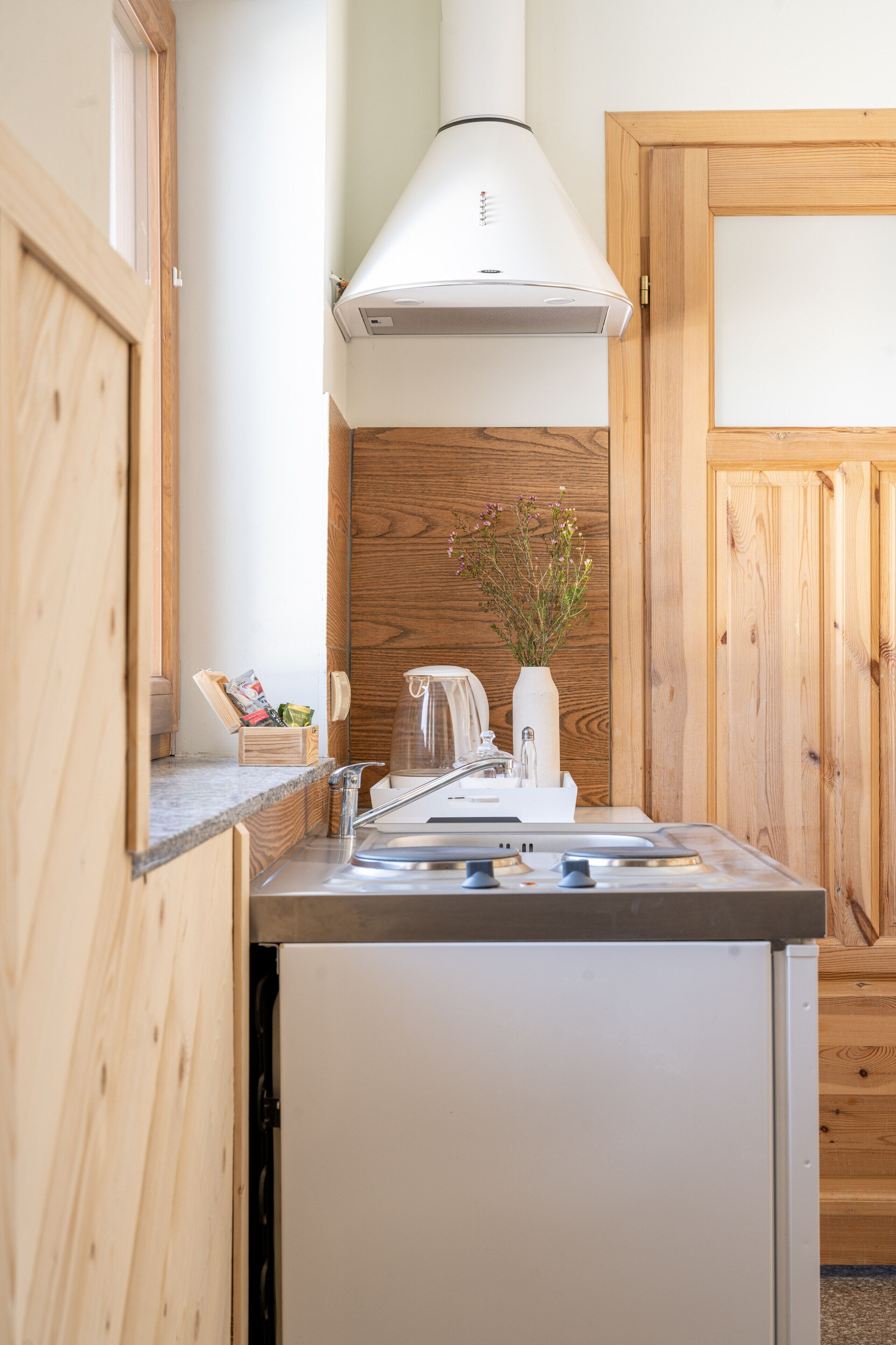 A compact kitchen with a built-in dishwasher, a white stove, and a wooden backsplash.