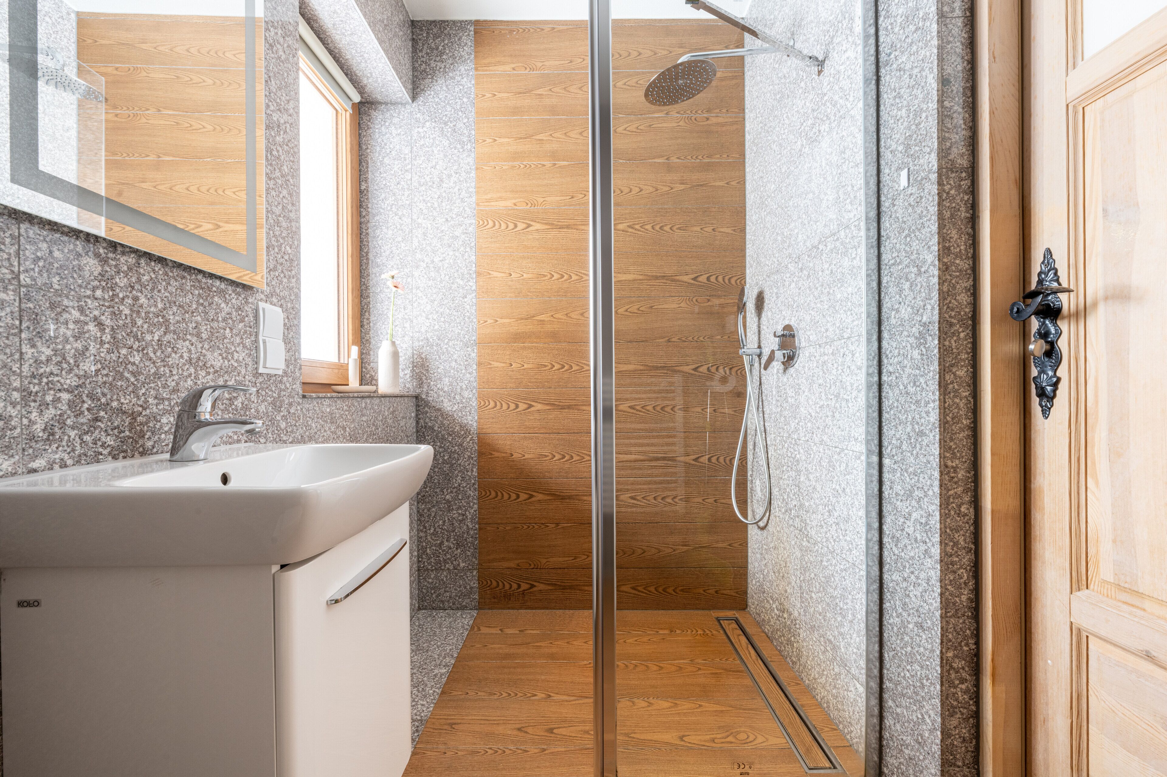 A modern bathroom with a glass shower enclosure, a sink, and a wooden vanity.
