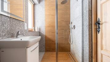A modern bathroom with a glass shower enclosure, a sink, and a wooden vanity.