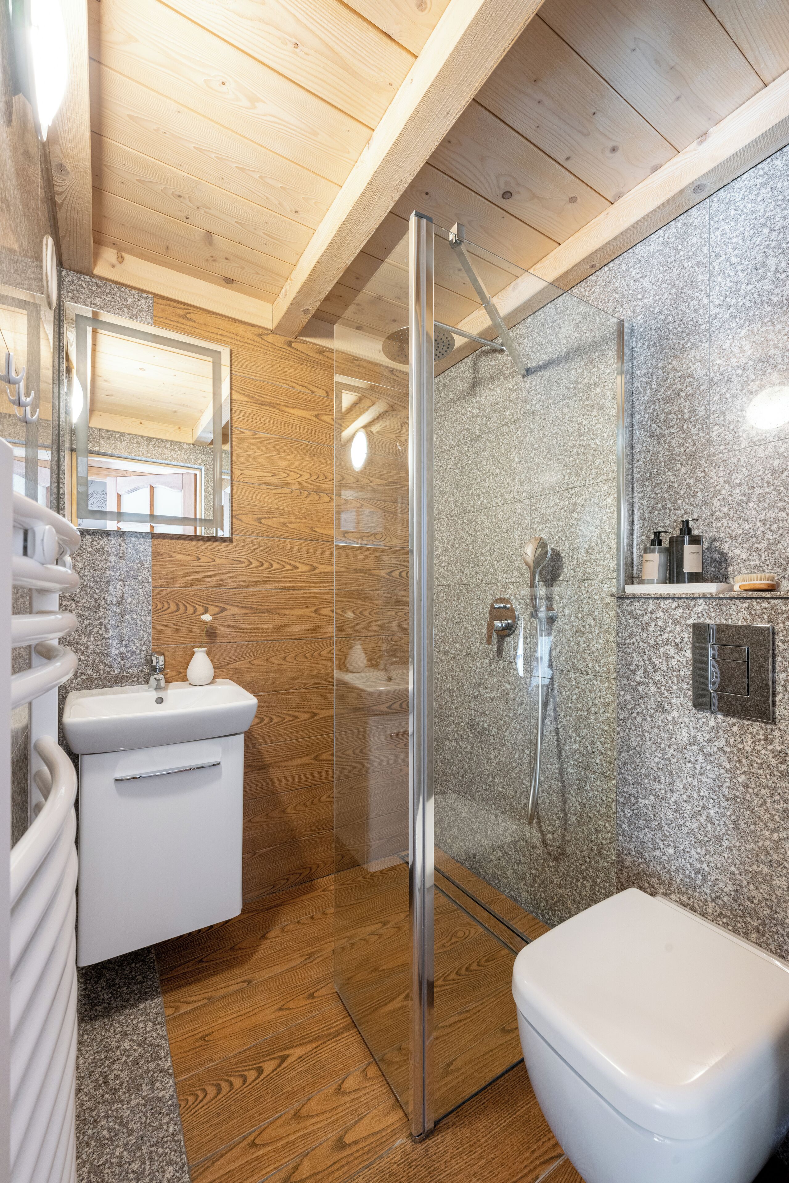 A modern bathroom with a glass-enclosed shower, a white sink, and a toilet.