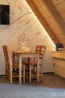 Un acogedor comedor de madera con una mesa y sillas, un televisor montado en la pared y una estantería llena de libros.