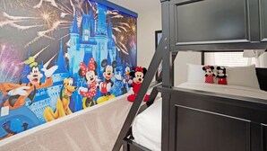 Quarto de hotel com beliche, um mural de personagens da Disney e vista para fogos de artifício.