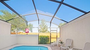 Piscina ao ar livre com área de terraço coberta, incluindo espreguiçadeiras e uma mesa.