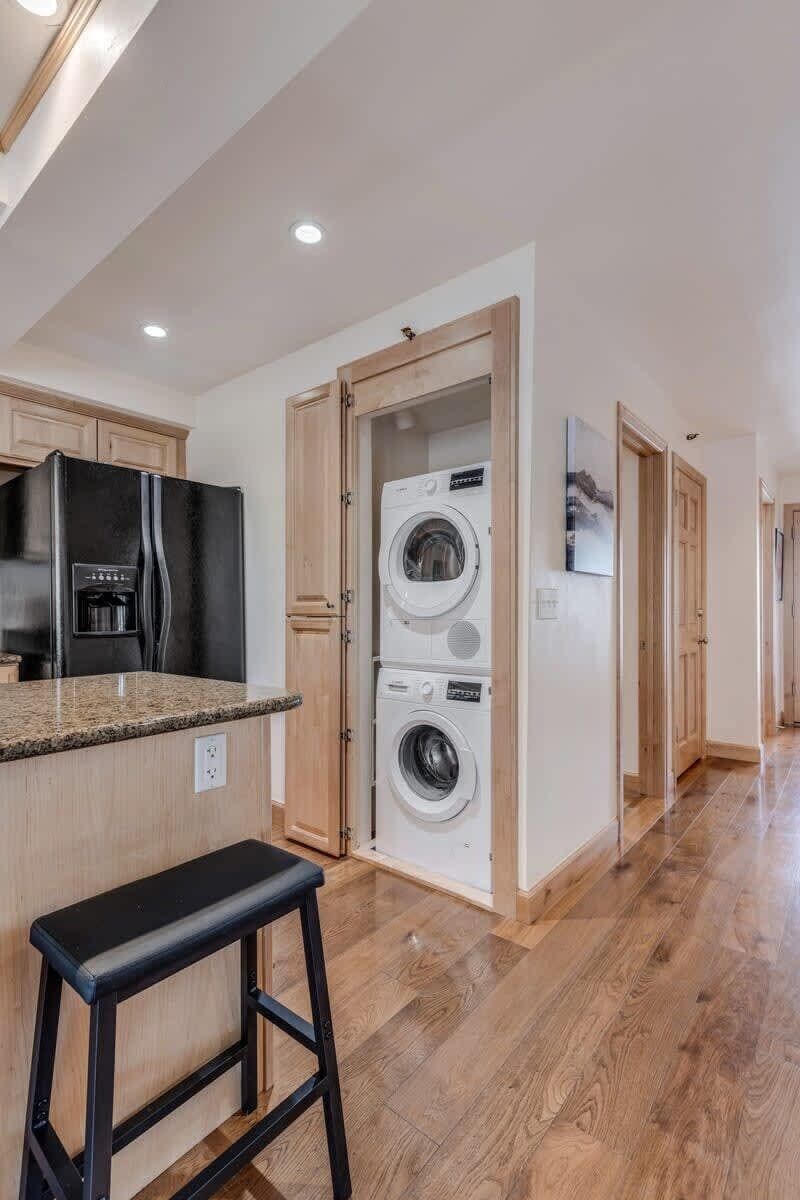 A modern kitchen with a built-in refrigerator, a washing machine, and a bar stool.