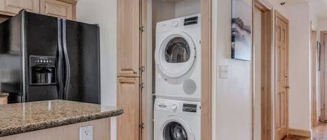 A modern kitchen with a built-in refrigerator, a washing machine, and a bar stool.