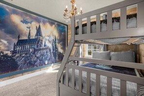 Uma cama beliche com um mural com tema de Hogwarts na parede.