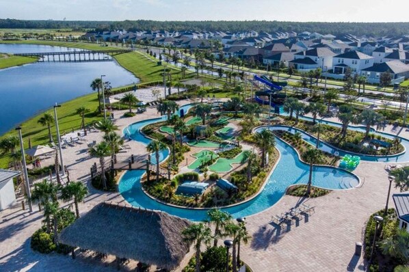 Enjoy a refreshing swim in the resort's central pool, surrounded by lush lawns and palm trees.
