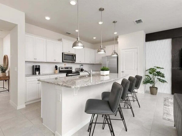 Enjoy cooking in this well-equipped kitchen with a central island, bar stools, and modern appliances.
