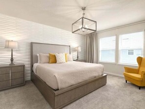 Relax in this serene bedroom with a large bed, a nightstand, and a comfortable armchair.