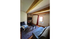Une pièce confortable avec un lit, une petite table, un téléviseur et une fenêtre avec des rideaux.