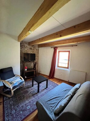 A cozy room with a bed, a small table, a TV, and a window with curtains. - Gite Biche, Maison Dans la Nature Avec Cheminée (Avène)