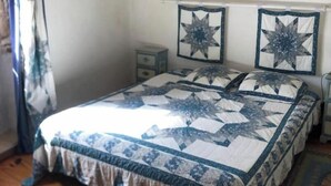 Une chambre à coucher avec un lit, des poutres en bois, une table de chevet et deux décorations murales représentant des étoiles.