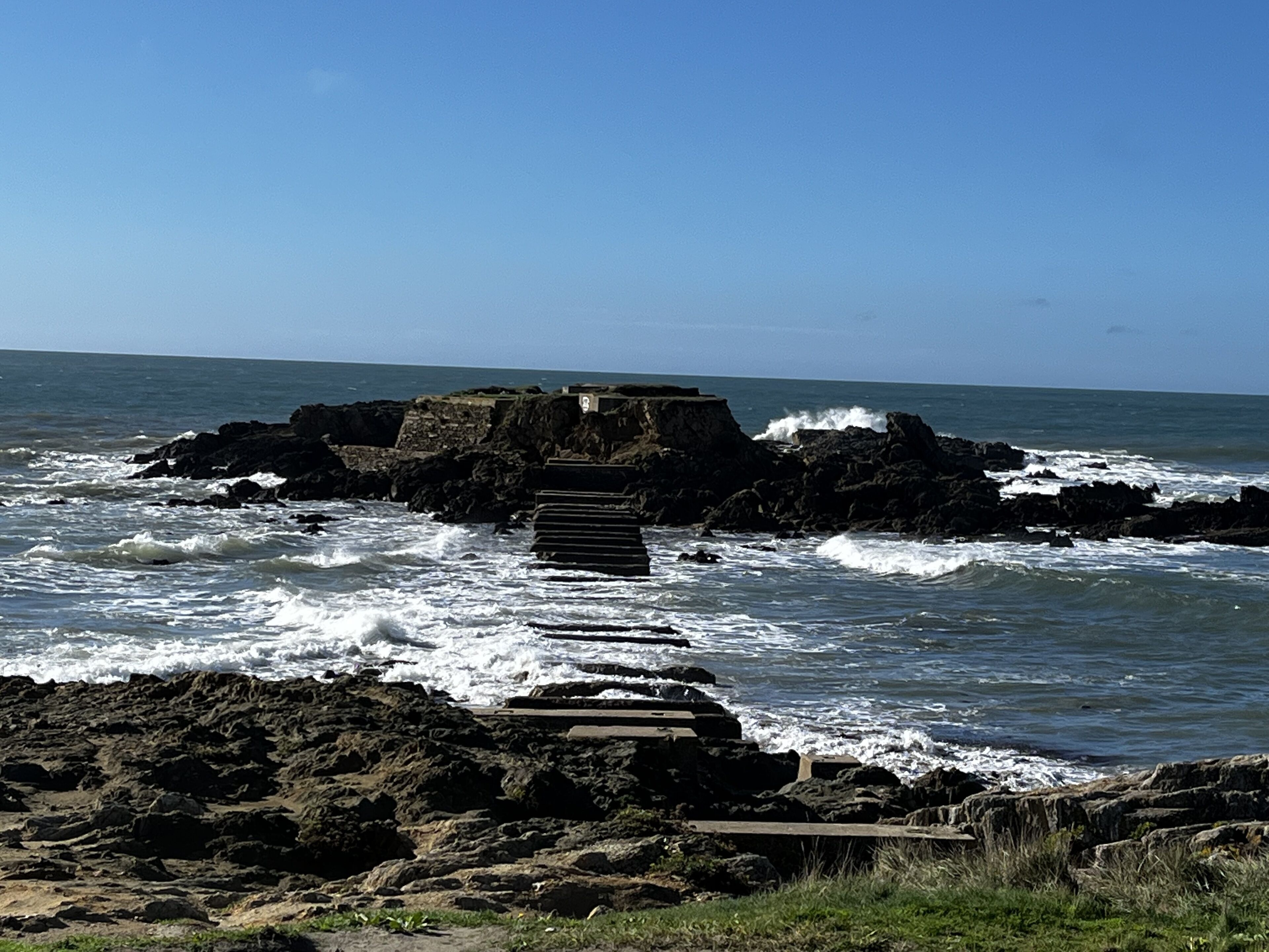 A rocky coastal area with a wooden staircase leading down to the water.