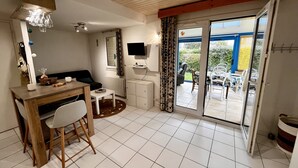 Una cocina moderna con comedor, un televisor montado en la pared y una puerta corrediza de vidrio que da a un patio exterior.